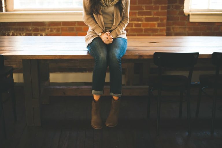 Woman sitting alone on wooden table, color photo