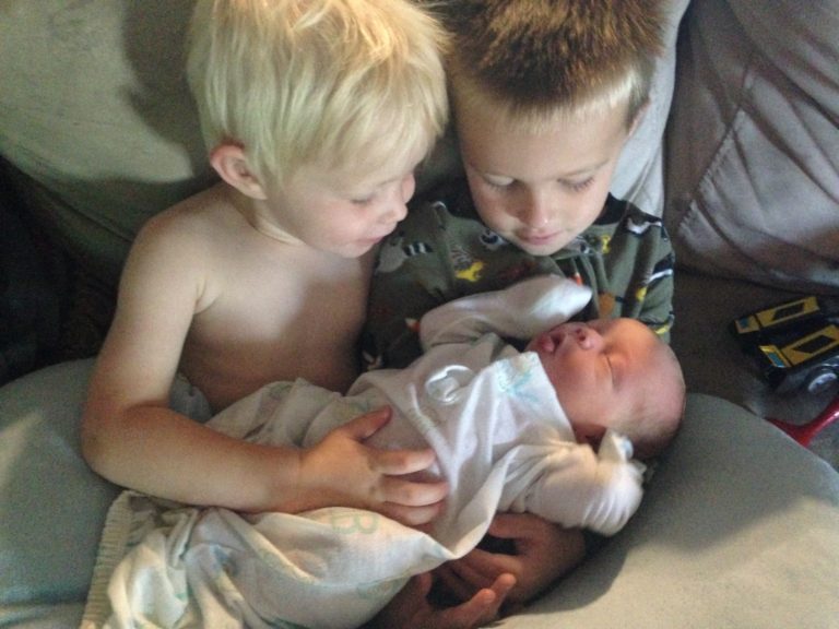 Brothers holding their baby brother