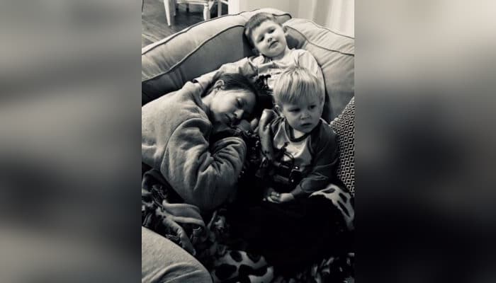 Mother and two young sons cuddled on couch