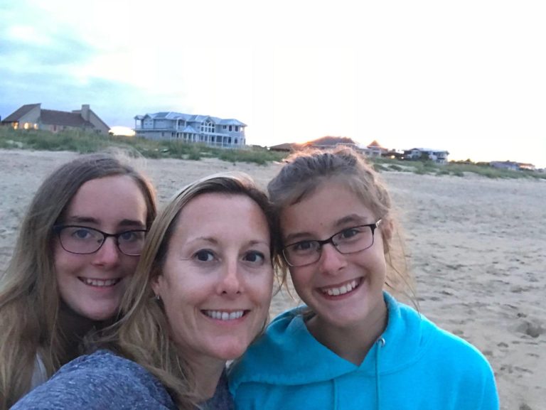 Mom and two teenage daughters smiling at camera