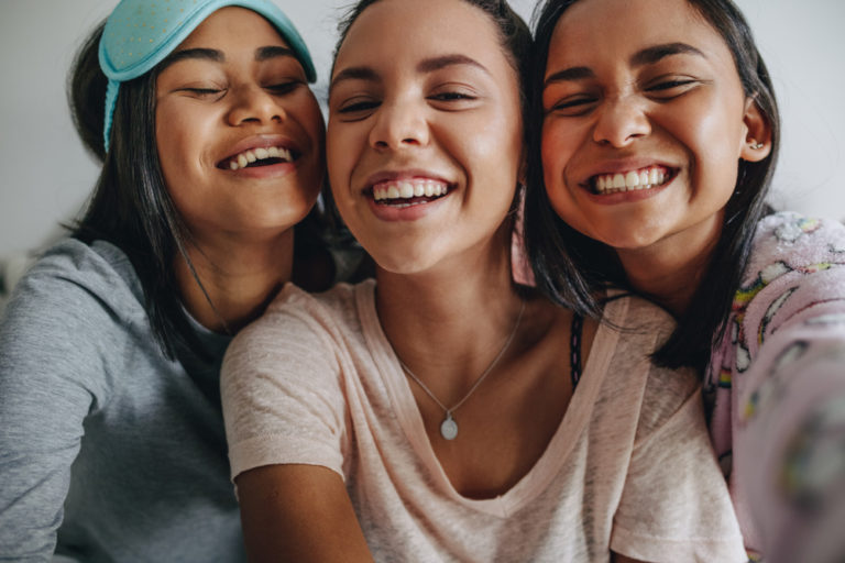 Three young teen girls smiling and laughing