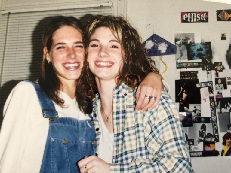 Two college friends hug and smile at the camera