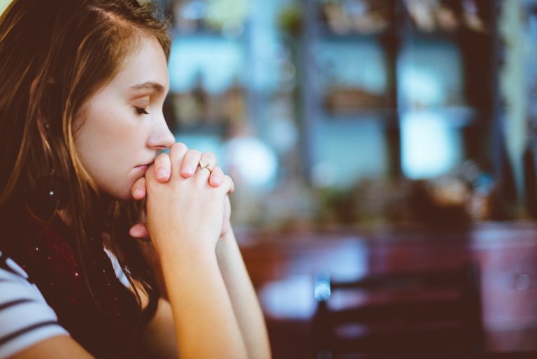 Profile shot of woman with eyes closed praying in church