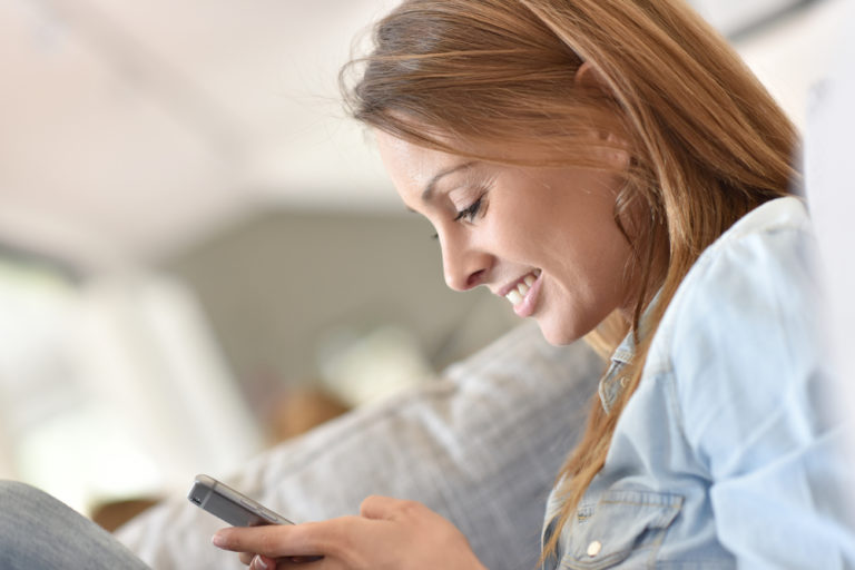 Woman smiling at smartphone in her hands