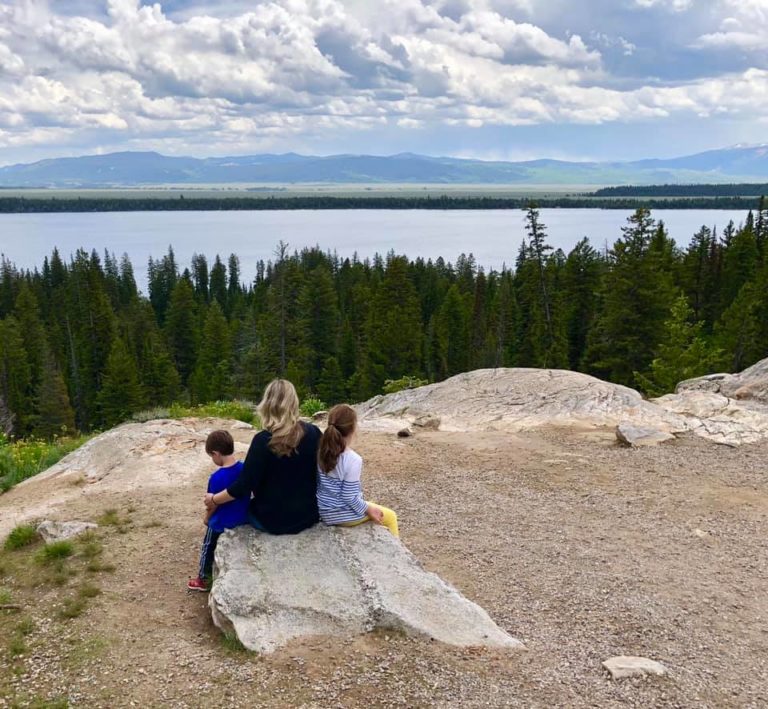 Mother sitting on a rock with two children looking at scenery