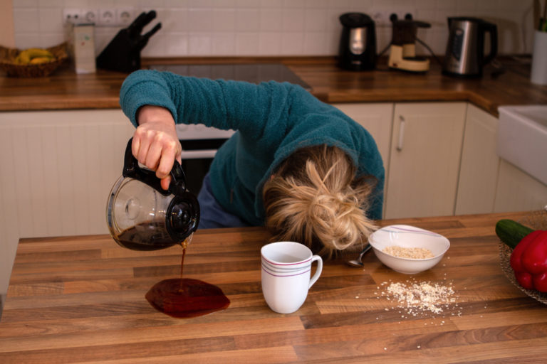 Tired woman spilling coffee with her head on table