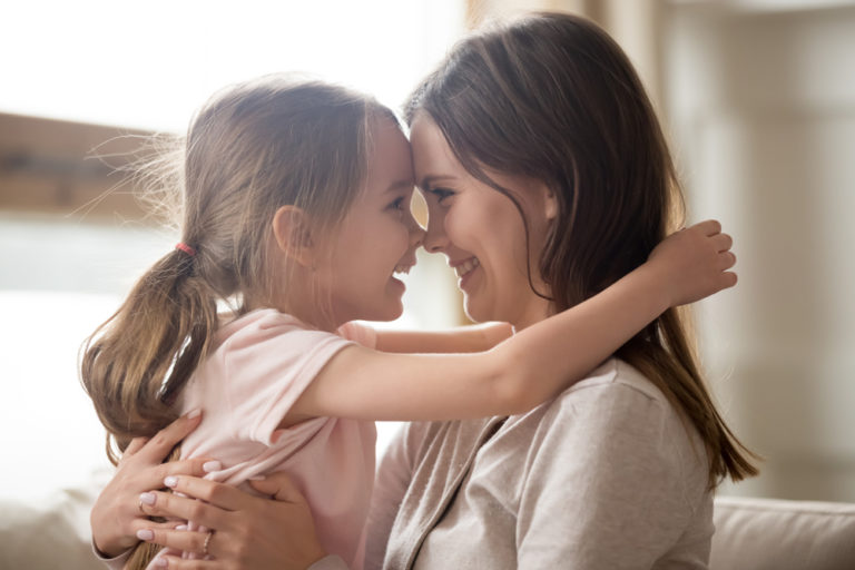 Mother and daughter touch foreheads and smile at each other