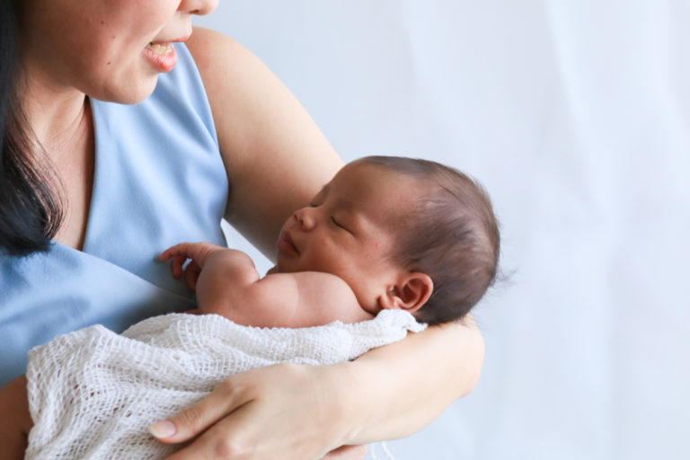 Woman cradling newborn son in her arms