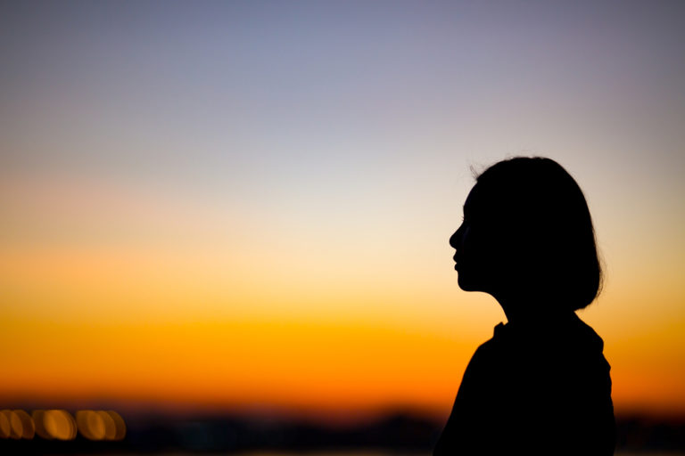 profile of a woman looking out over sunset
