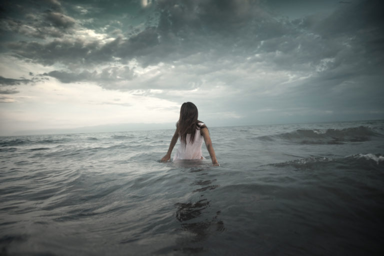 Woman in the middle of water with storm brewing around her