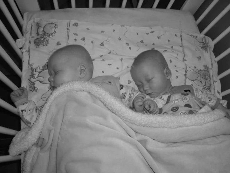 Twins sleeping in crib together