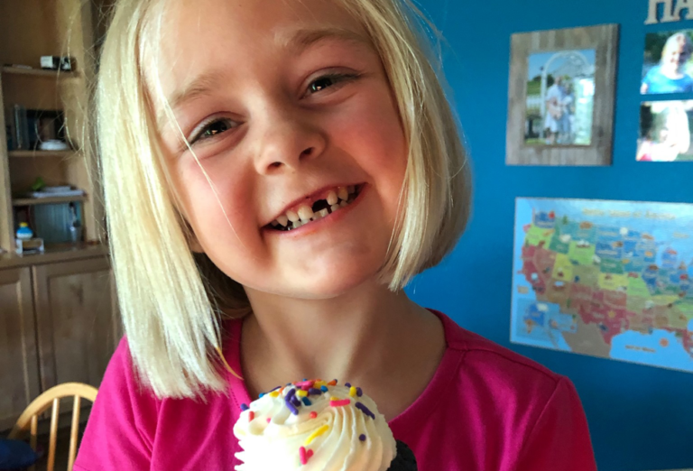 kindergarten child smiling holding a cupcake