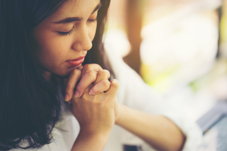 Woman praying with eyes closed