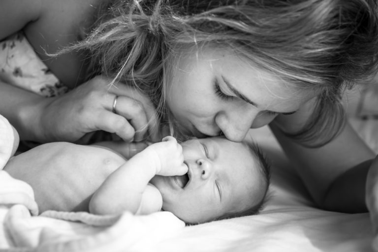 Mother kissing newborn baby in hospital