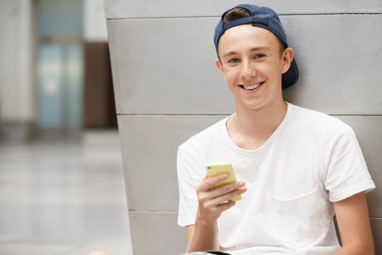 young teen boy holding cell phone