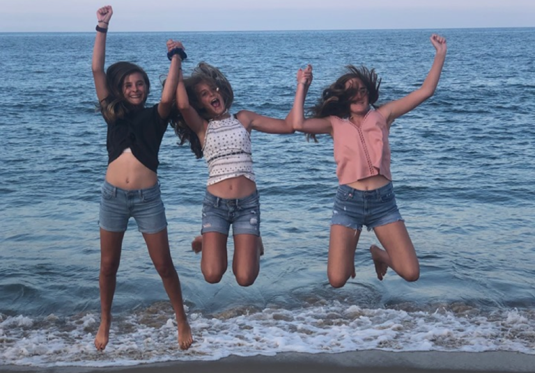 Three teen girls jumping on beach