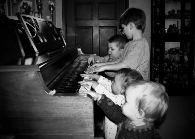 Four kids at piano black and white photo