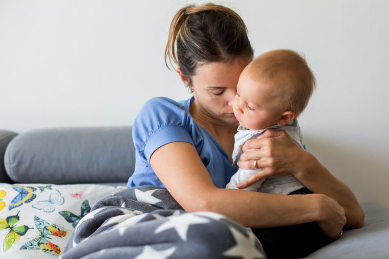Mother holding sick baby on couch