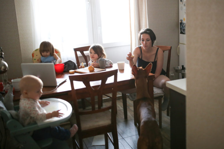 Tired mother sitting in kitchen with kids and dog