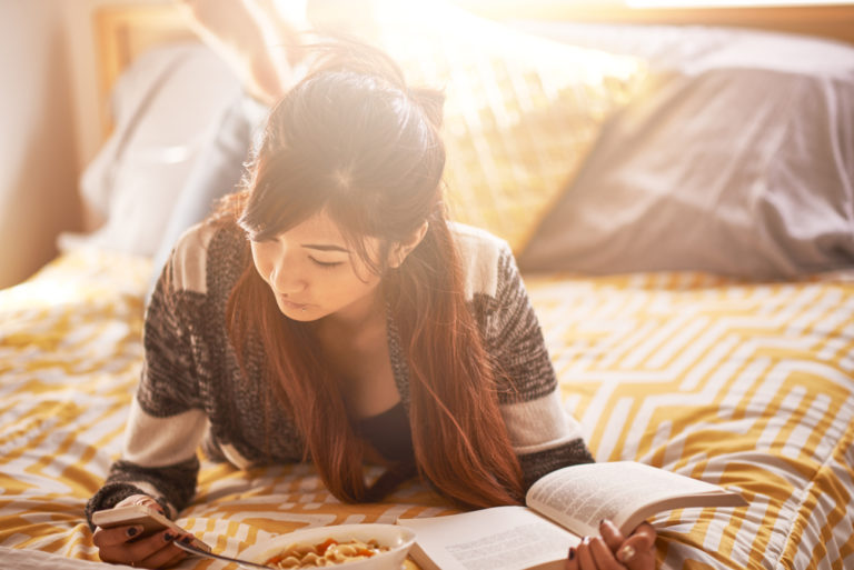 Teen girl writing in journal on bed