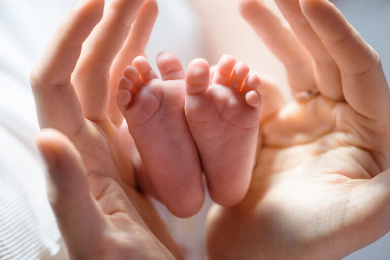 Hands holding baby feet sunlight