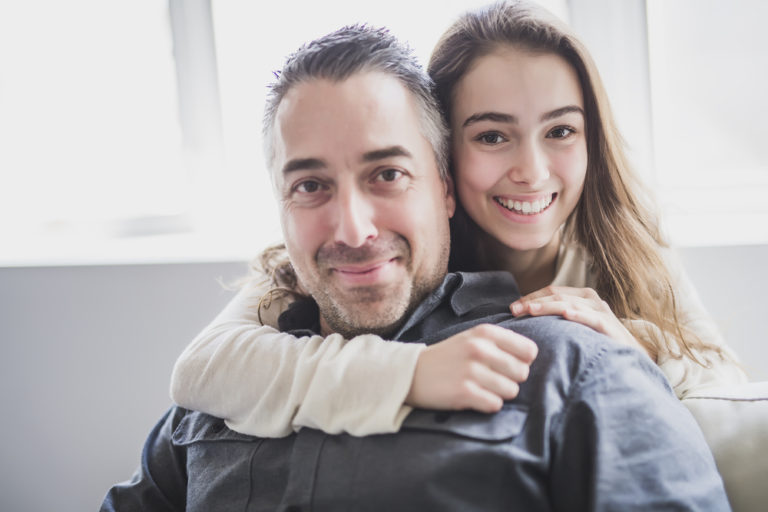 Father and teen daughter smiling