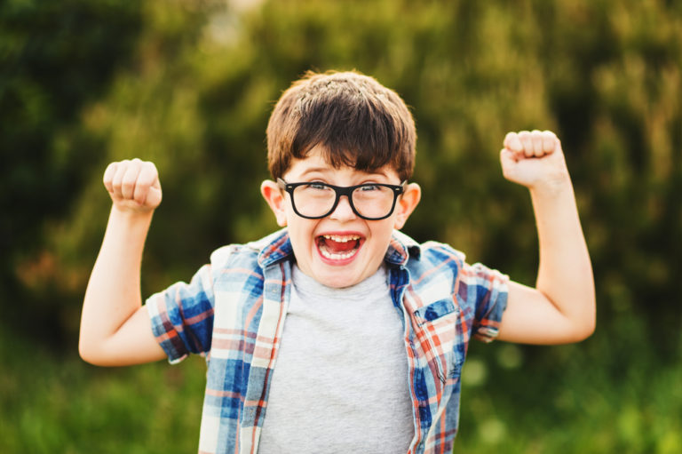 Little boy with glasses raising arms
