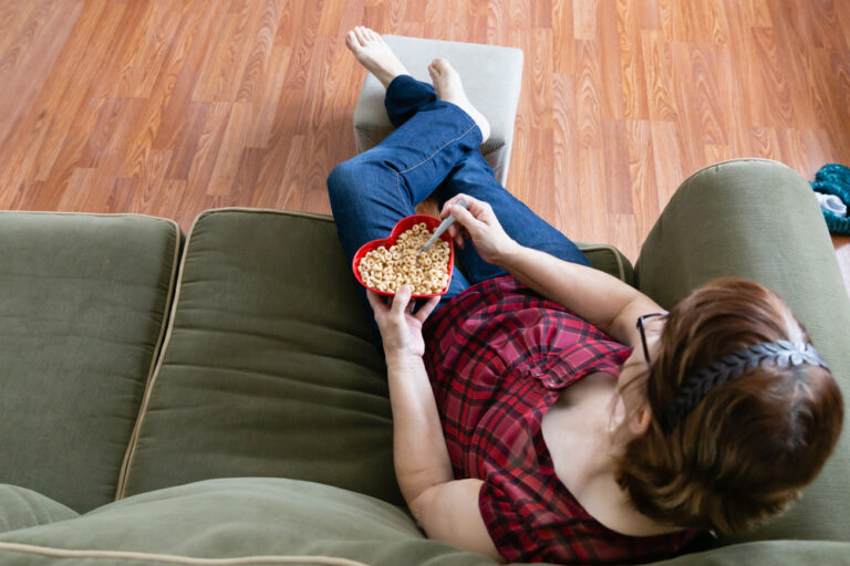 Woman on couch eating Cheerios