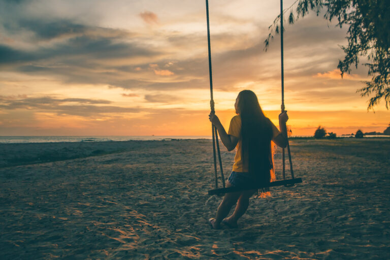 Woman on swing at sunset