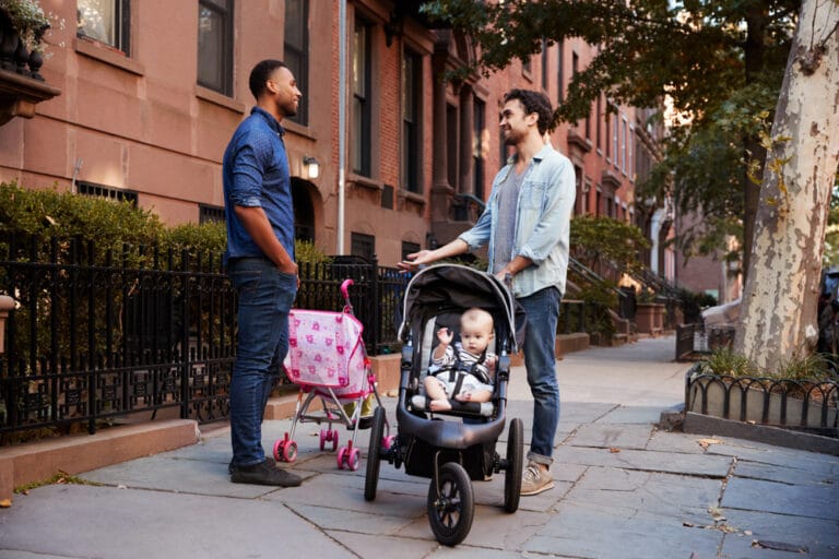 Two men with kids talking in street