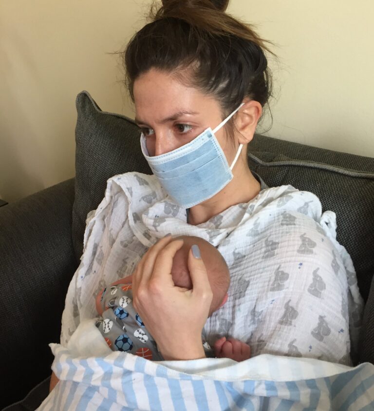 Woman wearing surgical mask holding baby