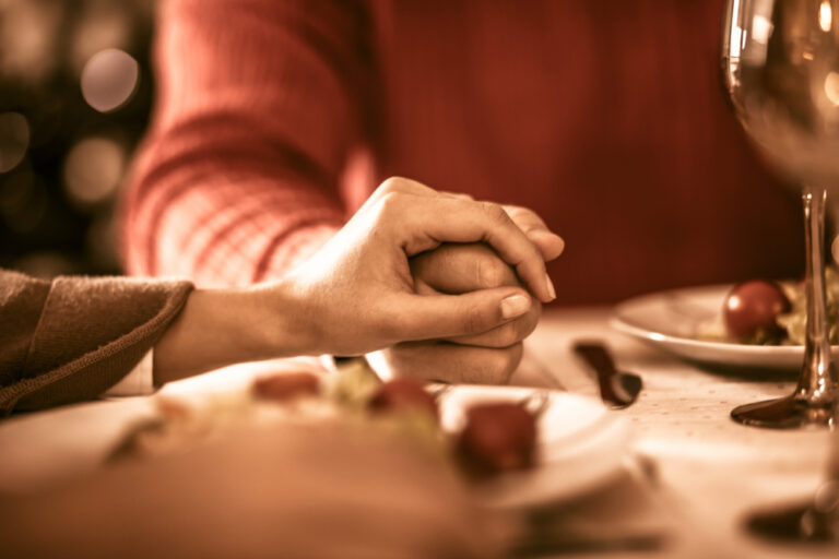 people holding hands at holiday table