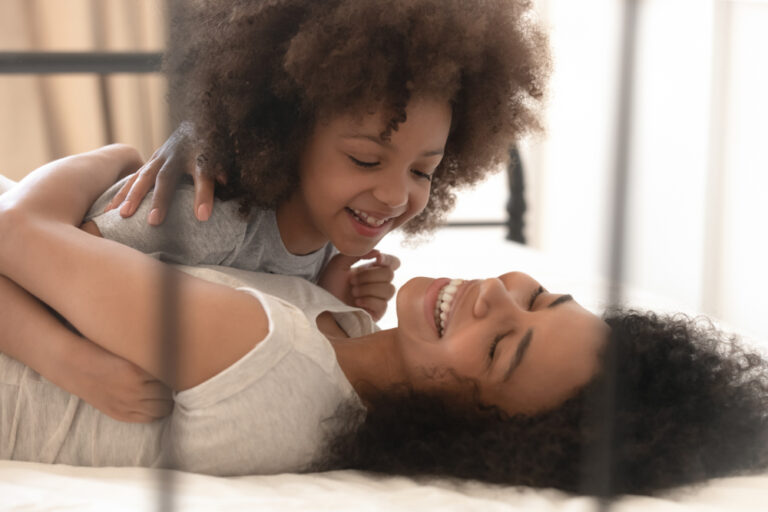 Mother and daughter laughing on bed