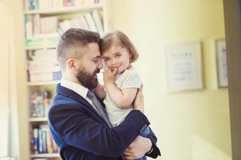 Dad in suit and tie hugging daughter