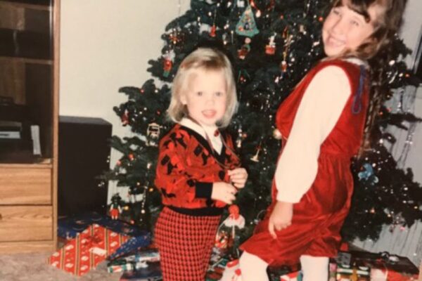 Two little girls by a Christmas tree in the 90s