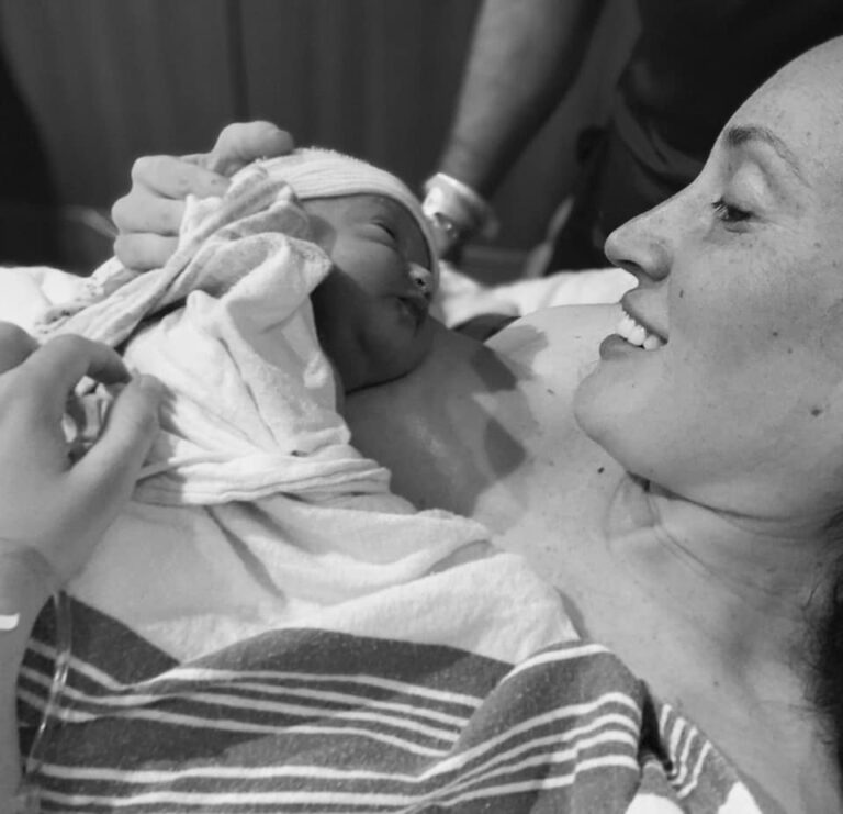 Mother holding newborn baby on her chest in delivery room