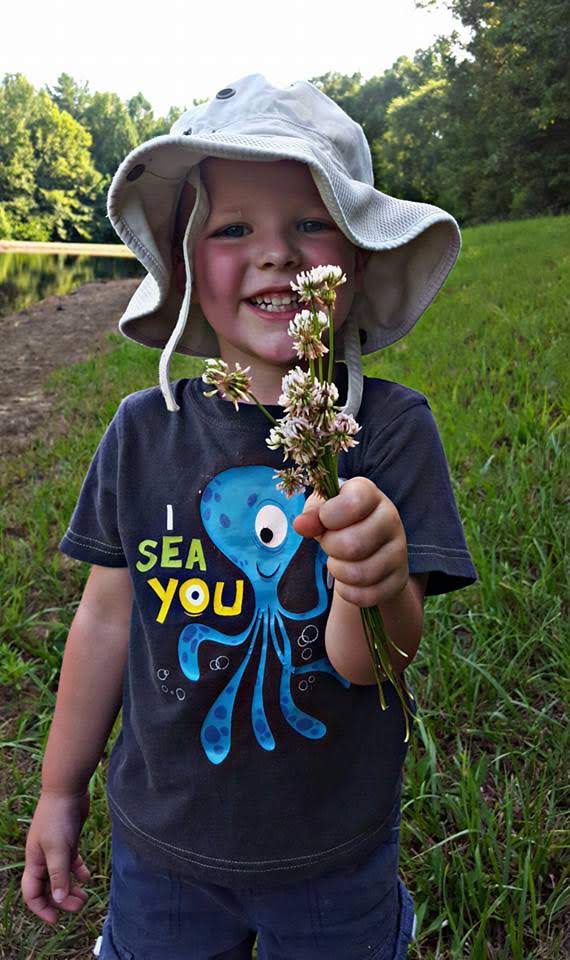 Smiling little boy holding flowers, color photo