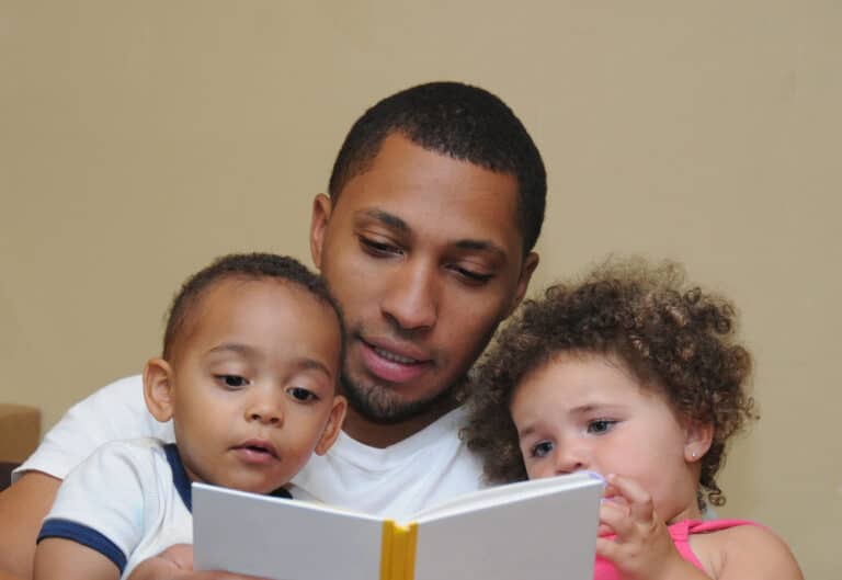 Dad reading books to his two young kids