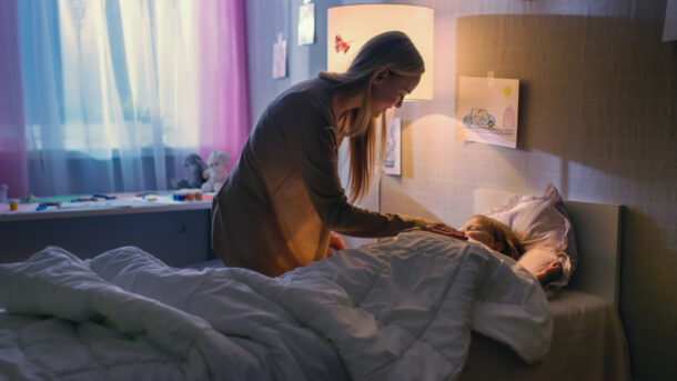 Mother tucking child into bed