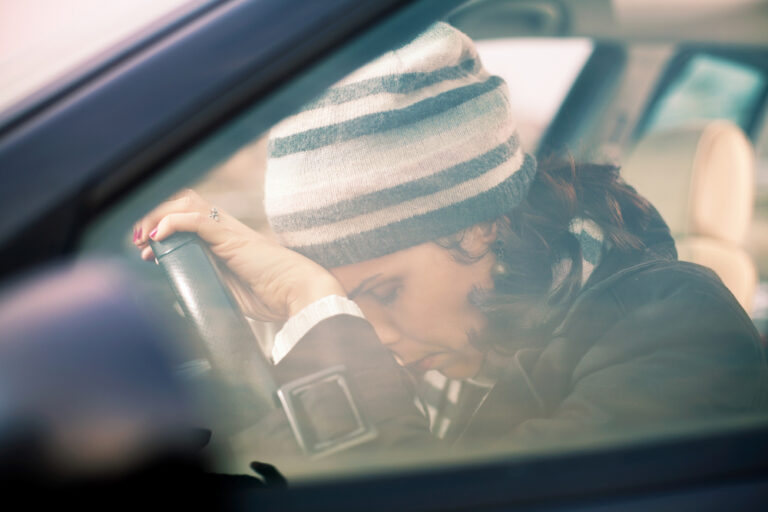 Woman in the car leaning head on wheel