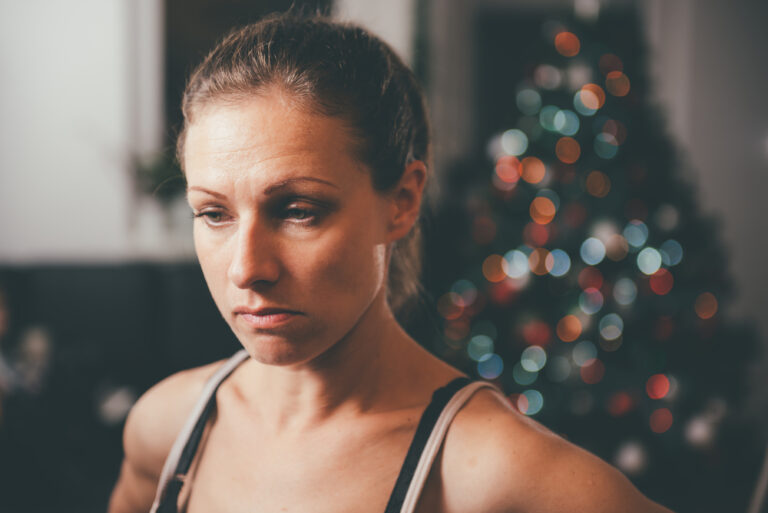 Sad woman with Christmas tree in backgroud