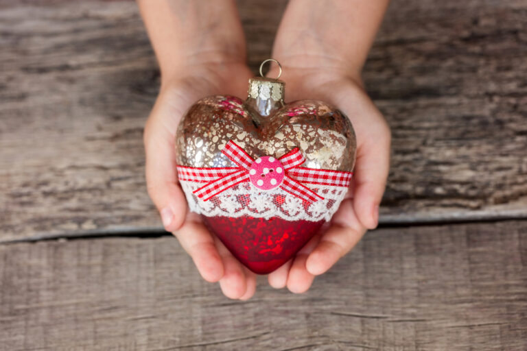 Child's hands holding Christmas heart ornament