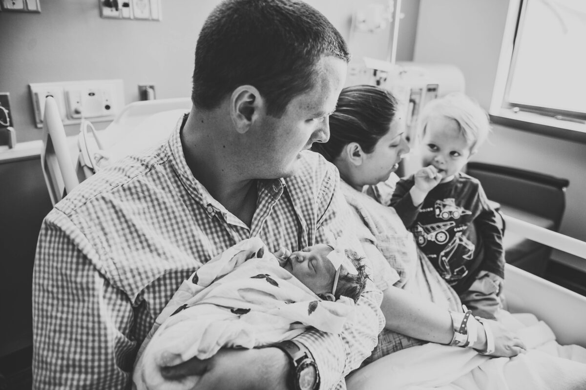 black and white photo, family of four in hospital with new baby