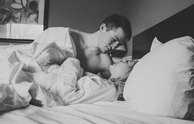 Husband and wife black and white photo smiling in bed