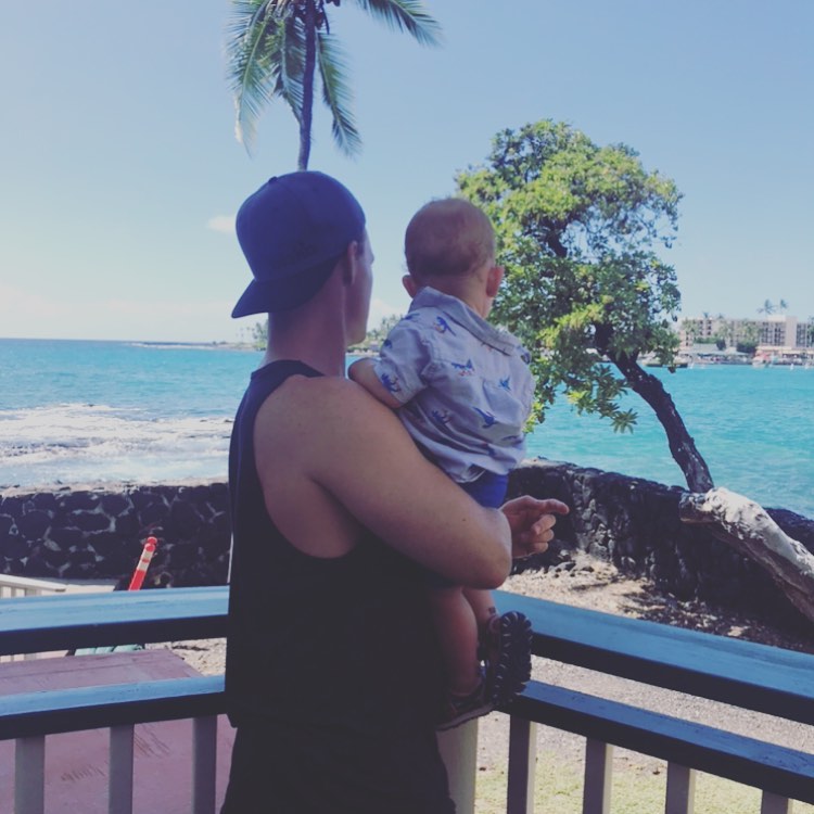 Man holding toddler on balcony by the ocean