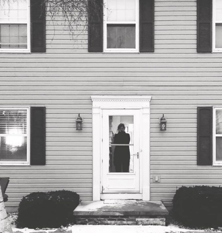 Mother standing at the door of a house, black and white photo