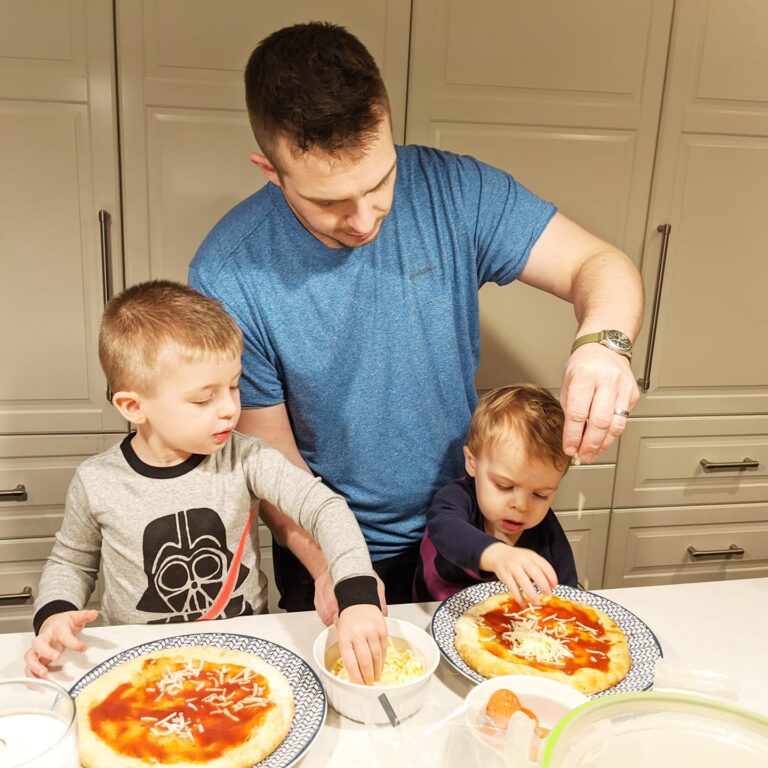 Father with two little boys cooking pizza