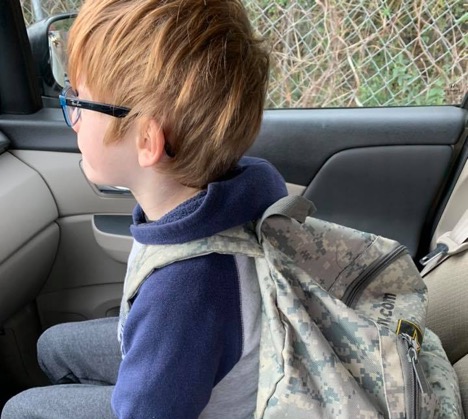Little boy in car wearing a heavy backpack