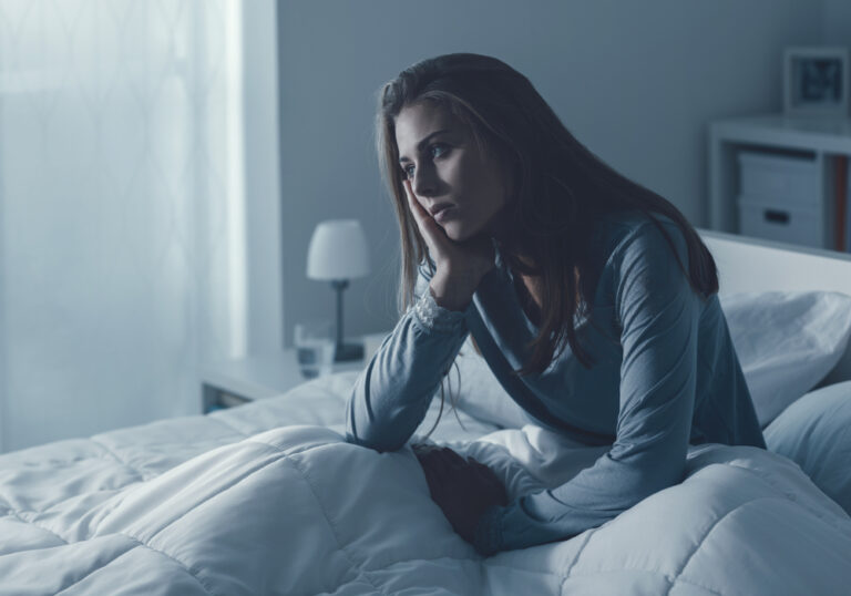 Woman awake in bed sitting up tired