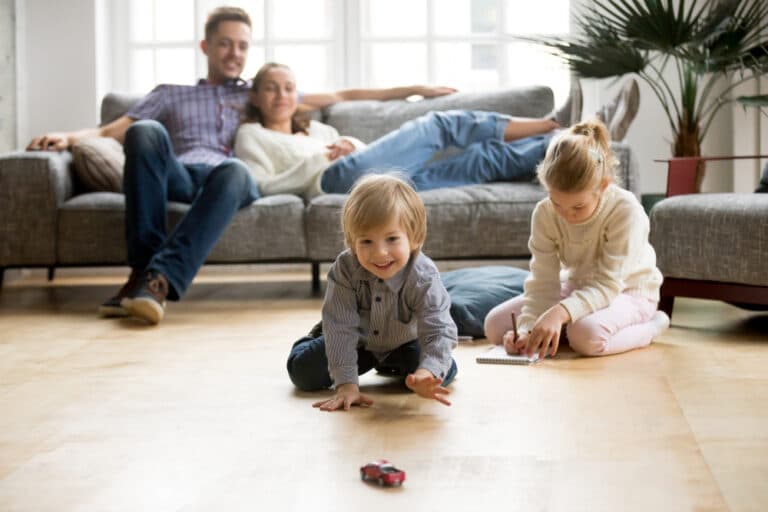Family relaxing in living room while kids play on floor